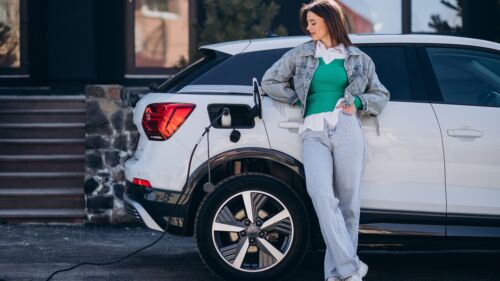 Woman charging her electric car with charging pistol