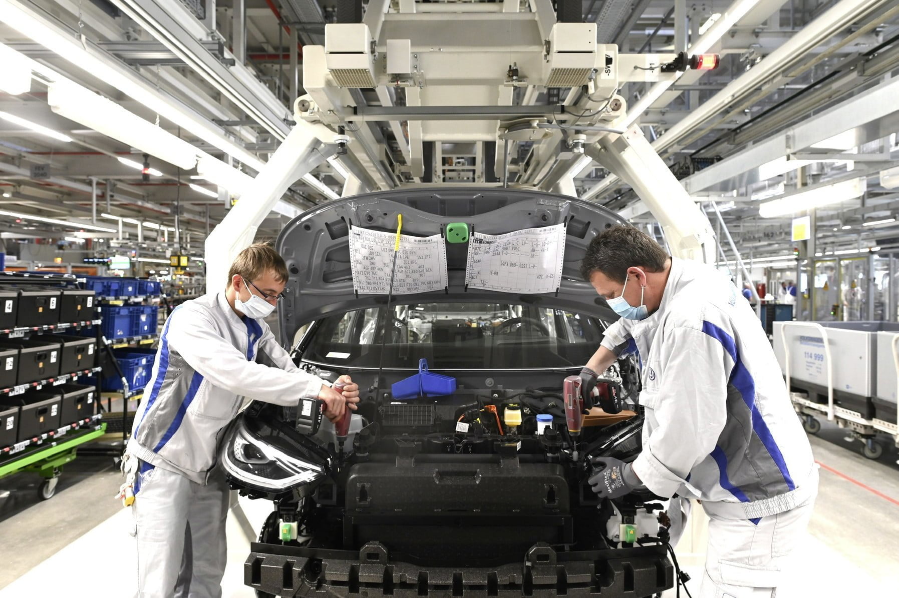 Two employees at Volkswagen in Zwickau install the headlight on the ID.3. For the restart of production, a catalogue of measures for health protection was agreed between the company and the works council, which provides for the wearing of mouth-nose protection at workplaces with a distance of less than 1. 5 metres from each other.